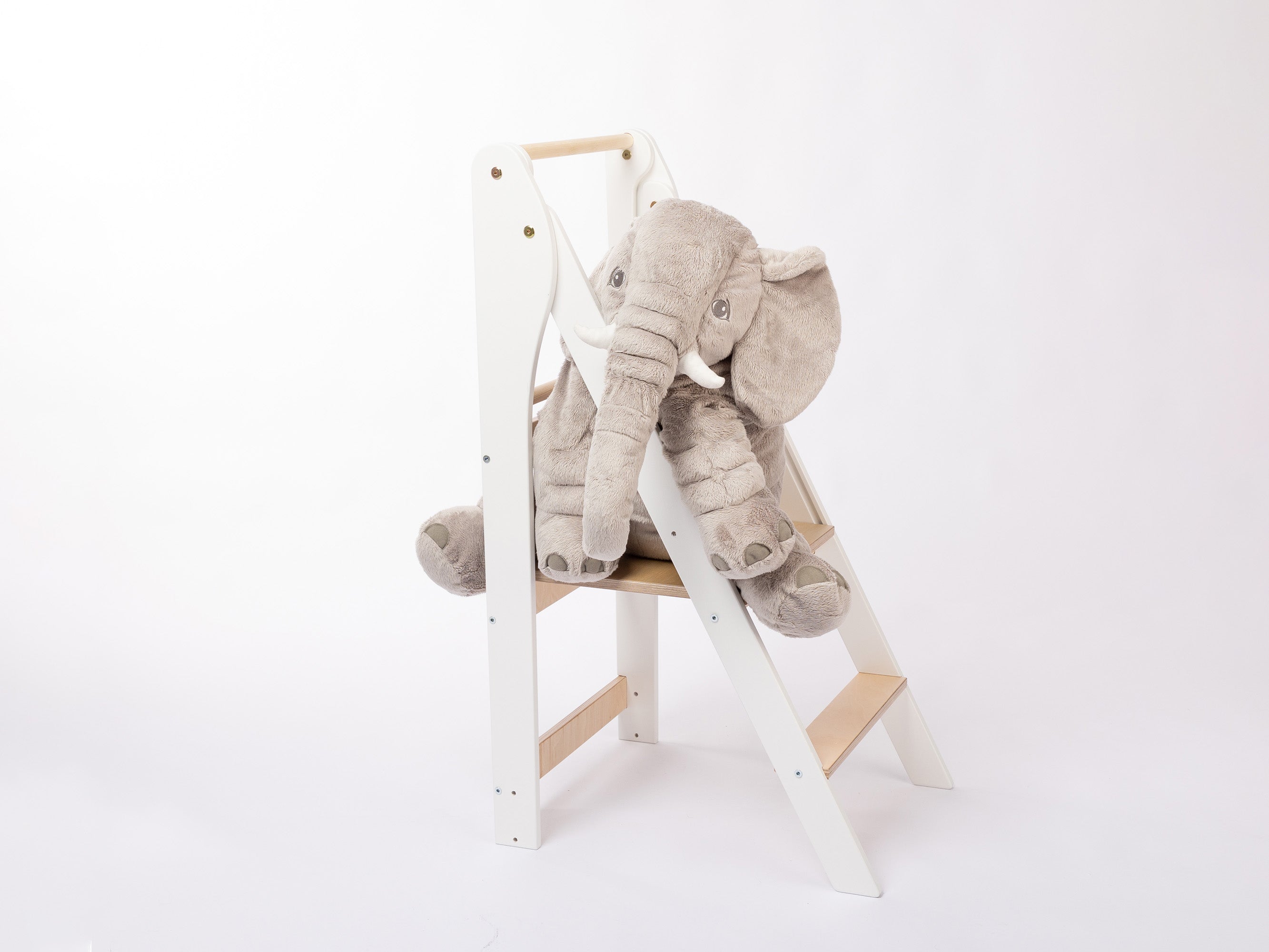 white montessori learning tower foldable with toy elephant on it
